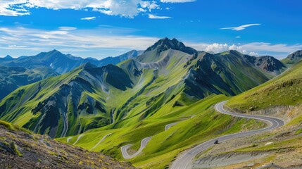 Scenic mountain pass with switchback curves winding up steep emerald slopes under a bright blue sky.