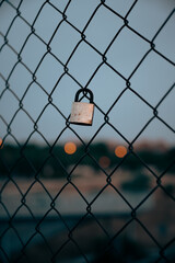 Padlock on metal net over sunset