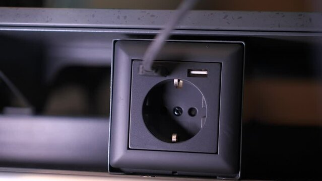 a girl passenger in a modern train carriage connects a USB cable to a socket