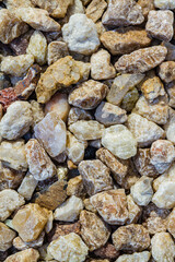 Close view of a collection of various stones and pebbles in different shapes, sizes, and colors, including shades of green, beige, and brown.