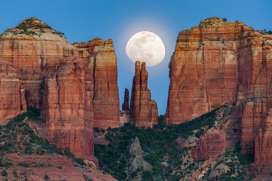 A waxing gibbous moon rises up over a sandstone spire in Sedona Arizona