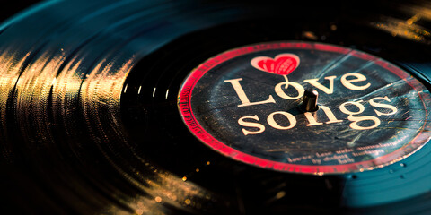 A record album with the words Love Songs written on it. The album is black and red. The album is old and has a vintage feel to it