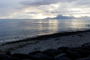 Rocky Beach Ocean And Moorea Island With Cloudy Sky