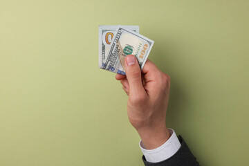 Money exchange. Man holding dollar banknotes on olive background, top view. Space for text