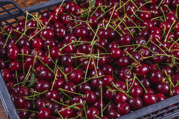 Ripe cherry in a plastic box on the table top view and side background