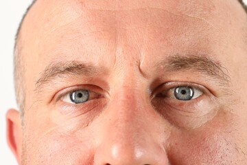 Man with beautiful blue eyes on white background, closeup