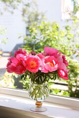 Beautiful pink peonies in vase on windowsill