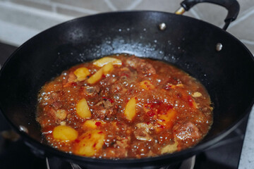 Potatoes roasted pork ribs being stewed in an iron pot on the stove.Sichuan flavor style.