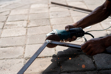 Person using angle grinder to cut metal outdoors