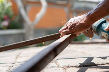 Person using angle grinder to cut metal rod