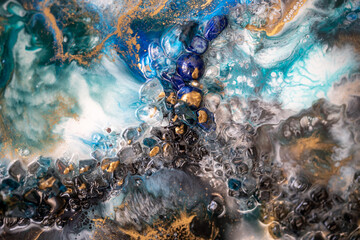 Closeup of unique texture of epoxy resin artwork product with artificial stones. Colorful picture with variety of blue azure pigments, paints. Painting made with style, technique of liquid fluid art.
