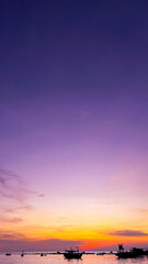 A breathtaking sunset over Teluk Beach, Labuan, with silhouettes of boats against a vibrant purple and orange sky, creating a serene and picturesque seascape.
