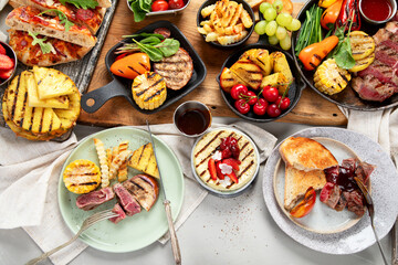 Table with grilled food. Pizza, corn, tomatoes, peppers, cooked meat. BBQ time