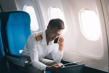 .Portrait of a trained airplane captain in uniform preparing to fly in a simulator cockpit.