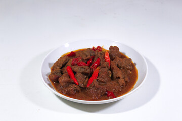 beef cooked in rendang with a garnish of cayenne pepper, served on a plate and photographed from the front