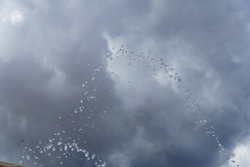 cloudy gray sky with a spray of water droplets floating down