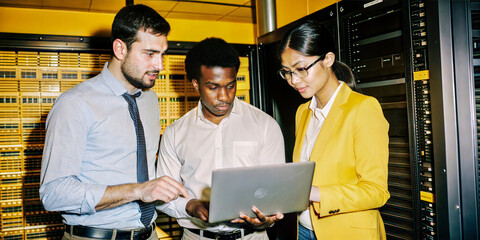 Business team analyzing data on laptop in server room