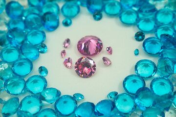 A group of Pink diamonds arranged in the middle of blue diamonds in a white background.Diamonds are highly valued as expensive pieces of jewelry..The sparkling light of the diamonds is beautiful..
