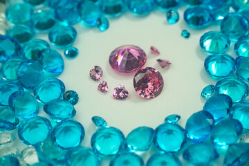 A group of Pink diamonds arranged in the middle of blue diamonds in a white background.Diamonds are highly valued as expensive pieces of jewelry..The sparkling light of the diamonds is beautiful..