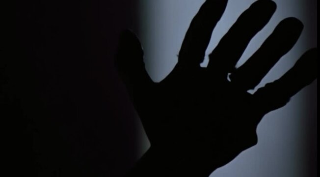 Silhouette of a zombie hand on white background in slow motion
