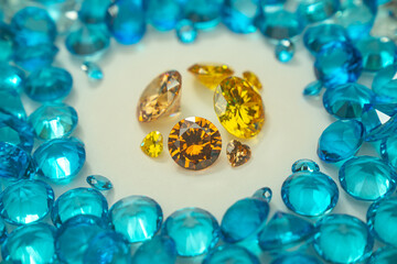 A group of Yellow diamonds arranged in the middle of blue diamonds in a white background.Diamonds are highly valued as expensive pieces of jewelry..The sparkling light of the diamonds is beautiful..