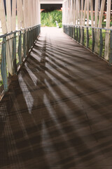 The moonlight at night shines on the wooden suspension bridge, and the shadow of the railing is...