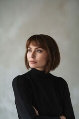 A woman in black turtleneck sweater with her arms crossed.