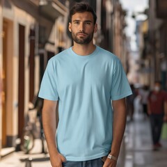 A man wearing a light blue t - shirt standing on a street.