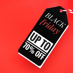 Fototapeta premium A black sale tag on a red background with the words Black Friday up to 70% off, signaling special discounts, deals, prices or promotions