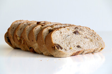 7 slices of healthy whole grain raisin and walnut brown bread against white background, healthy lifestyle and eating concept, balanced diet