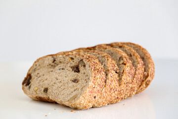 5 slices of whole grain brown raisin and walnut bread against white background, healthy eating and lifestyle concept