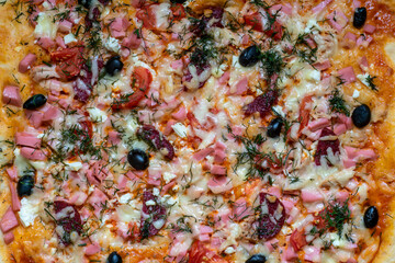 Homemade pizza close-up.Ingredients: sausage, chicken, cheese, tomatoes, olives, spices.