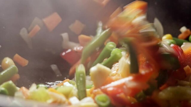 The process of cooking multicolored sliced vegetables in a frying pan. Vegetables for healthy proper nutrition close-up