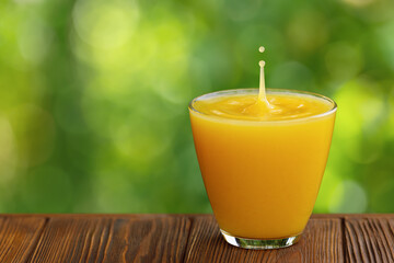 glass of orange juice with splash and drop on wooden table