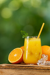 glass of cold orange juice or summer cocktail with ice and straw