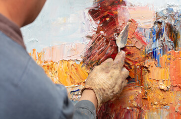 The artist paints a picture with a spatula