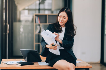 Asian businesswoman talking on phone, using laptop, looking at screen, entrepreneur manager consulting client by call, looking at computer screen, discussing project, reading information