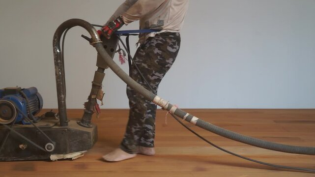 A worker polishes a dusty wooden floor