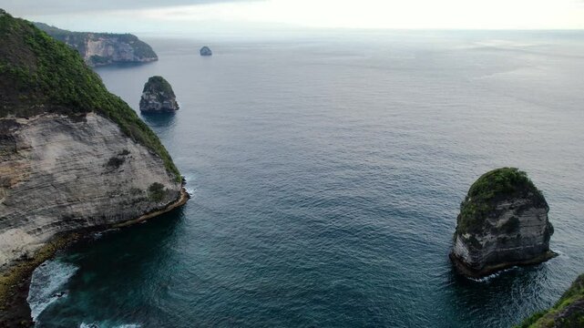 aerial drone shot panning showing the beautiful coast sea with green hills in hte Nusa Penida area in Kellingking showing the tropical paradise in bali Indonesia