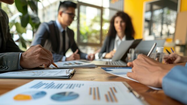 A diverse group of business professionals in suits having a meeting in a modern office space and discussing financial reports and data. AIG535