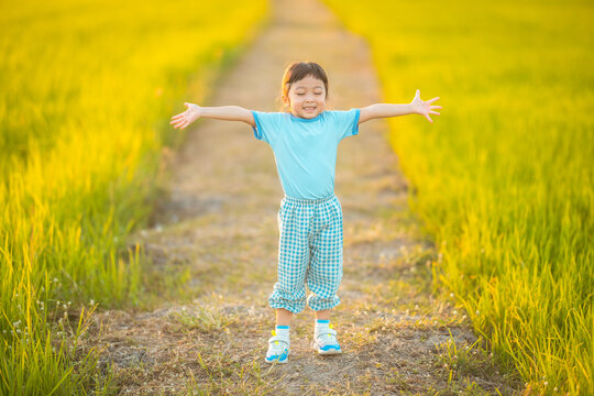 baby girl with happy time on freedom in emotional in outdoor by run play on grasses floor in rice fields blue dress