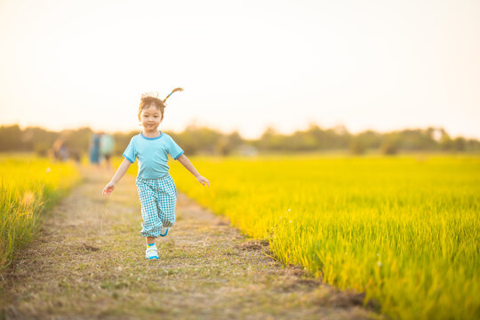 baby girl with happy time on freedom in emotional in outdoor by run play on grasses floor in rice fields blue dress