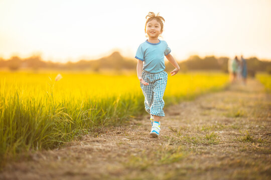 baby girl with happy time on freedom in emotional in outdoor by run play on grasses floor in rice fields blue dress