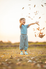 baby girl with happy time on freedom in emotional in outdoor by play throw leaves on grass floor in blue dress