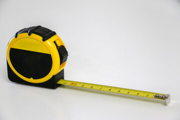 Black and yellow retractable tape measure against white background