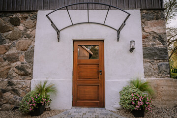 Blome, Latvia - September 11, 2023 - A wooden door with a metal awning on a stone and stucco...