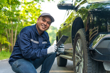 Happy professional asian automobile mechanic repairman wearing uniform and protection glove checking the wheel in workshop and looking at camera. Car service and maintenance, Repair service.