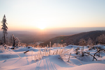 Winter sunset in the Moravian-Silesian Beskids, eastern Czech Republic. Snow-covered peaks, vibrant orange-pink sky, serene nature, and frosted trees create an idyllic, picturesque winter scene