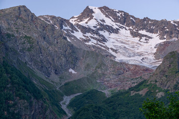 The formation of a glacier at the top of the mountain. Melting ice high in the mountains. A vacation trip to the mountains. Landscape with a view of the glacier. Snow-capped mountains in summer.