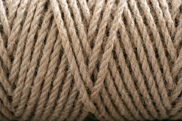 Tightly wound coil of natural fiber rope, displaying its robust texture and earthy beige color. Organic appearance make it ideal for backgrounds, crafts, and eco-friendly projects.